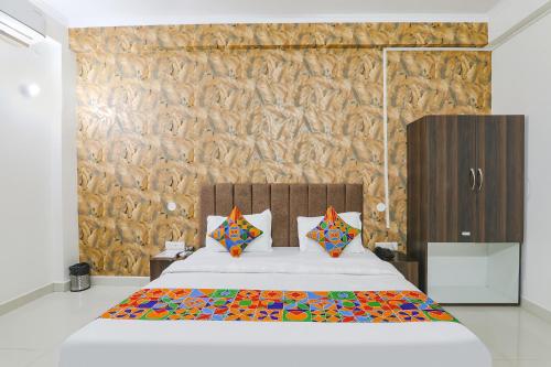 Un dormitorio con una cama blanca con sábanas y almohadas coloridas. en FabHotel The Villa I en Prayagraj