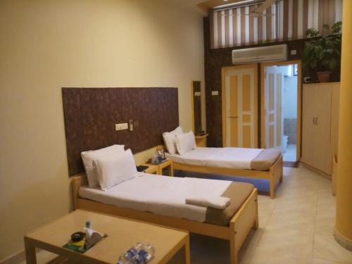 um quarto de hotel com duas camas e uma mesa em Krishna Palace em Jhālāwār