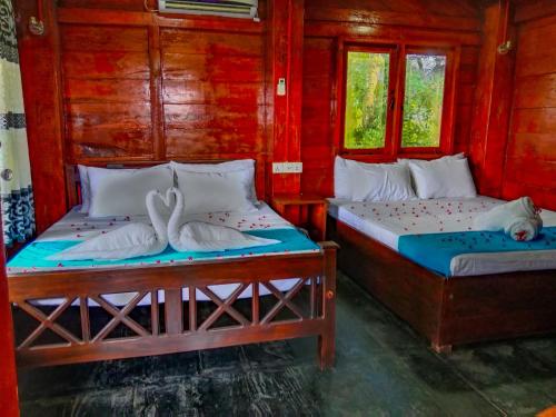 - 2 lits dans une chambre dotée de murs rouges et de fenêtres dans l'établissement Ceylon Amigos Eco Resort, à Sigirîya