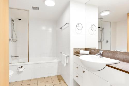 a white bathroom with a sink and a tub at Glam & Stylish Broadbeach 2BR Apartment in Gold Coast