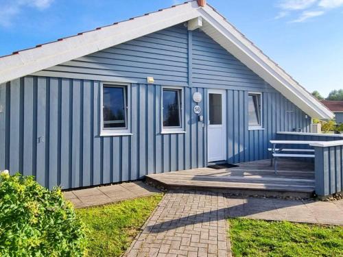 un cobertizo azul con un banco en un porche en 6 person holiday home in Otterndorf, en Otterndorf