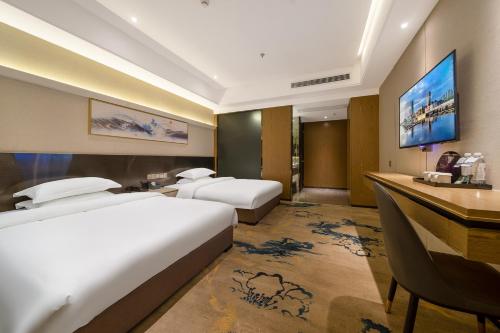 a hotel room with two beds and a desk at Guangzhou Yunzhu Hotel in Guangzhou