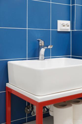 a white sink in a bathroom with blue tiles at Lama Hostel in Ivano-Frankivsʼk
