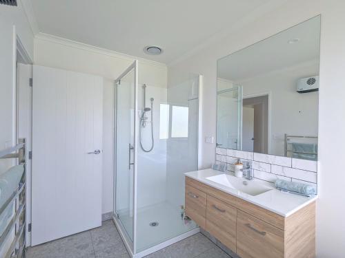 baño blanco con ducha y lavamanos en Beautiful Brand New Four-Bed Home near Redwood en Rotorua