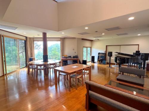 una habitación con mesas, sillas y un piano en 123MUSIC(イズサンミュージック), en Atami