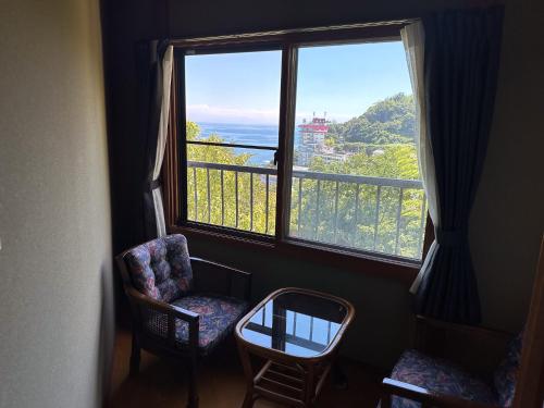 a room with two chairs and a large window at 123MUSIC(イズサンミュージック) in Atami