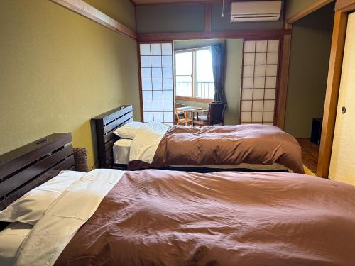a room with three beds and a window at 123MUSIC(イズサンミュージック) in Atami