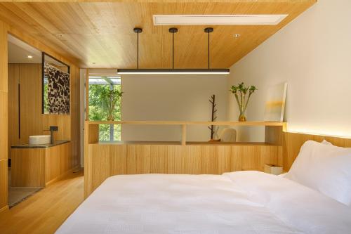 a bedroom with a white bed and a wooden ceiling at La Petronilla Boutique Hotel Moganshan in Deqing