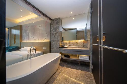a bathroom with a tub and a bed and a sink at Guangzhou Yunzhu Hotel in Guangzhou