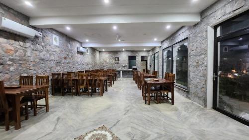 un ristorante con tavoli e sedie in legno e un muro di pietra di Hem Vilas a Sawai Madhopur