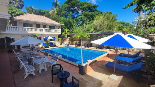 a pool with chairs and umbrellas next to a house at Le Watwam Hotel in Siem Reap