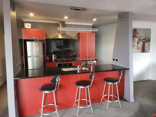 una cocina con armarios rojos y taburetes de bar en De Vine Martinborough #26, en Martinborough
