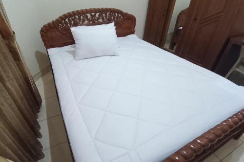 a bed with white sheets and a pillow on it at SPOT ON 93376 Roemah Ambarrukma 185 Syariah in Yogyakarta