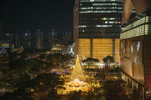 a christmas tree in the middle of a city at night at Lotte Hotel World in Seoul