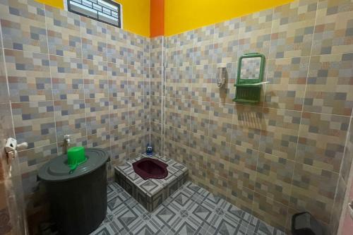 a bathroom with a toilet in a tiled room at SPOT ON 93378 Lona Guest House Syariah in Parit