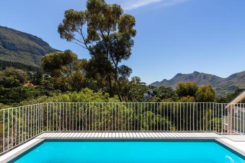 a swimming pool with a fence and mountains in the background at Elite Retreats - Hillside Villa 2 - power backup in Cape Town