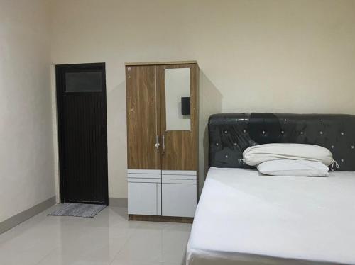 a bedroom with a bed with a black headboard at OYO 93388 Enjoy Homestay & Cafe in Sungguminasa