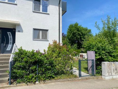 uma casa branca com uma cerca e alguns arbustos em 1,5 Zimmer Apartment in S-Bahn Nähe, 35 qm, max 4 Pers, zentral, private Terasse, Internet 250 MBit em Gärtringen