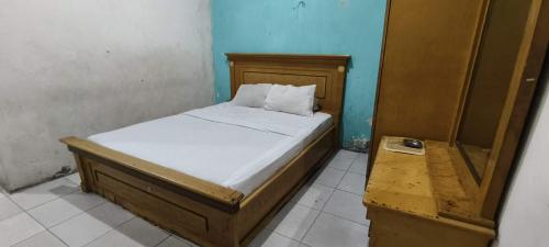 een kleine slaapkamer met een bed met witte lakens bij OYO 93400 Pondok Tawing Rumbih in Banjarmasin