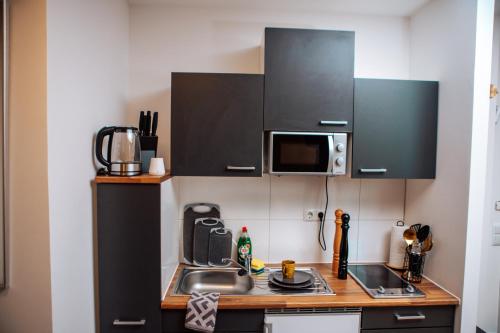 eine kleine Küche mit einer Spüle und einer Mikrowelle in der Unterkunft Central-Living yellow - Wifi - Netflix - City in Essen