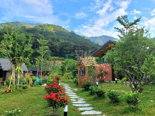 a garden with a pathway with red flowers and a house at Anna Little Garden - Homestay Sóc Sơn - Thong House in Hanoi