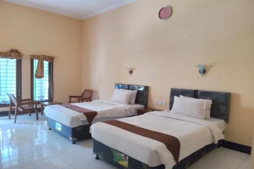 a hotel room with two beds and a clock on the wall at Capital O 93391 Golden Manggis Hotel in Narmada