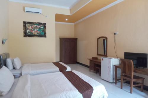 a hotel room with two beds and a television at Capital O 93391 Golden Manggis Hotel Near SMKN 1 Lingsar in Narmada