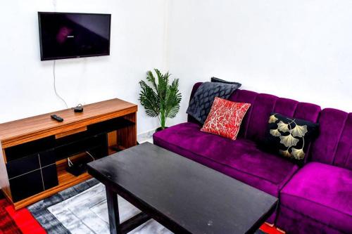 eine lila Couch in einem Wohnzimmer mit Klavier in der Unterkunft Davis Homes in Kitale