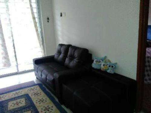 - un canapé en cuir noir dans le salon avec une fenêtre dans l'établissement AD Homestay Kuantan, à Kuantan