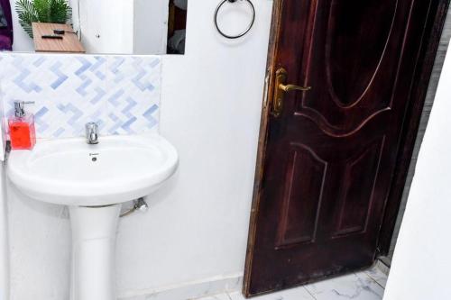ein Badezimmer mit einem Waschbecken und einer braunen Tür in der Unterkunft Davis Homes in Kitale