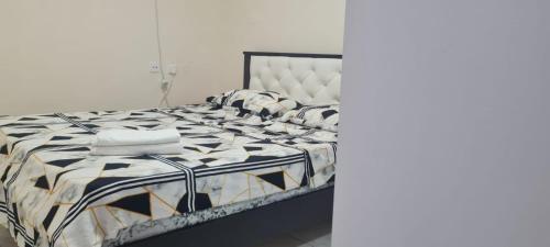 a bed with a black and white comforter and pillows at Светлая и уютная квартира у моря in Haifa