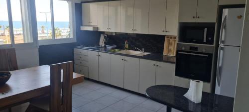 a kitchen with white cabinets and a sink and a refrigerator at Светлая и уютная квартира у моря in Haifa