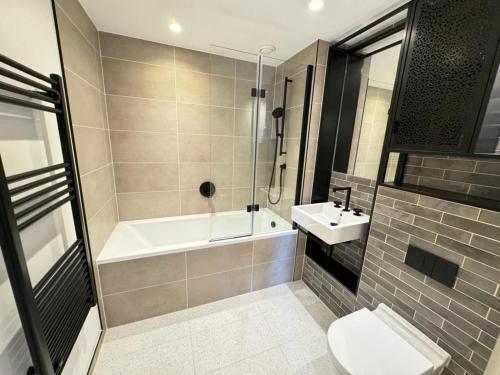 a bathroom with a tub and a toilet and a sink at Excel Riverside 2 Bed in London