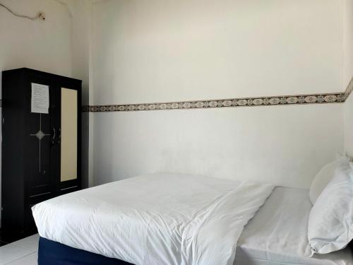 1 dormitorio con cama blanca y cabecero en OYO 93412 Kost Irma Syariah, en Parepare