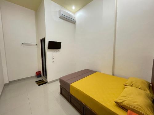 ParepareにあるOYO 93414 Wisma Ratu Syariahのベッドルーム(黄色いベッド1台、テレビ付)