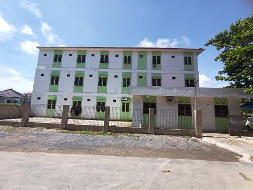 een wit gebouw met groene ramen en een hek bij Hotel O Pondok Kula Rumbih Syariah in Sungairasau
