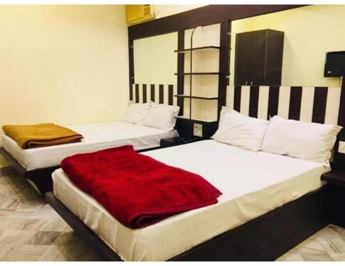 two beds in a room with a red blanket on them at Hotel Satyam, Kanpur in Kānpur