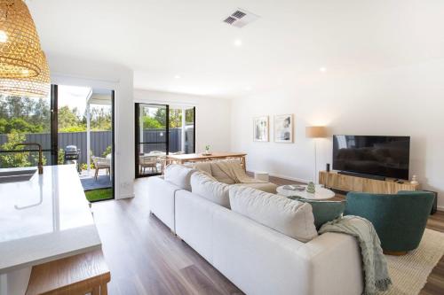 a living room with a white couch and a tv at Kirkland - Pet Friendly - 5 Mins Walk to Beach in Culburra Beach