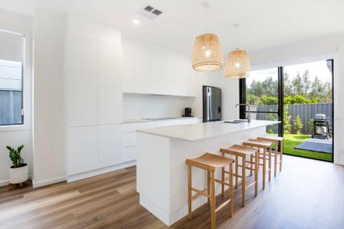 a kitchen with white cabinets and bar stools at Kirkland - Pet Friendly - 5 Mins Walk to Beach in Culburra Beach