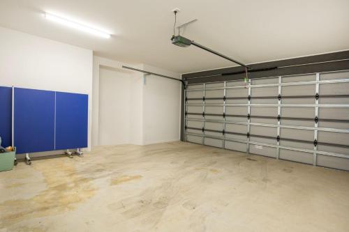 an empty garage with blue garage doors in a room at Kirkland - Pet Friendly - 5 Mins Walk to Beach in Culburra Beach