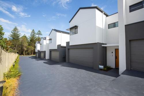 a row of white houses on a driveway at Kirkland - Pet Friendly - 5 Mins Walk to Beach in Culburra Beach