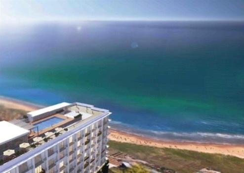 a building on the beach with the ocean in the background at Ocean Breeze Condo in Negombo