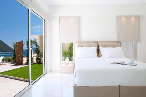 a bedroom with a white bed and a large window at OFF White Villas in Vasiliki