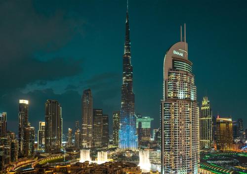 BURJ ROYALE - Luxury 2 bedroom apartment with full burj Khalifa & fountain view- DELUXE في دبي: اطلالة ليلية على مدينة ذات مبنى طويل