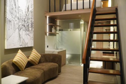 uma sala de estar com um sofá e uma escada em Posto Dormire Sudirman em Jakarta