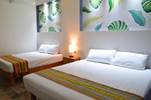 a room with two beds and a painting on the wall at Hotel Axolotl in Puerto Escondido