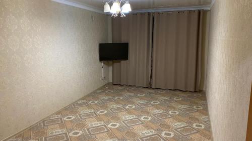 a room with a television and a tiled floor at Квартира in Oral