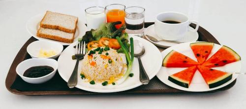un plateau de nourriture avec du riz et des fruits et une tasse de café dans l'établissement The Space Airport Hotel Chiang Rai, à Ban Du