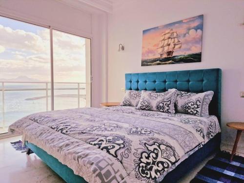 a bedroom with a blue bed and a large window at The bleu sea in Tunis