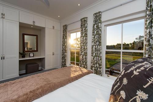 ein Schlafzimmer mit einem Bett und einem großen Fenster in der Unterkunft Greenhill Farm Parklands Cottage - 2 bedroom 4 guests - Private House in Plettenberg Bay